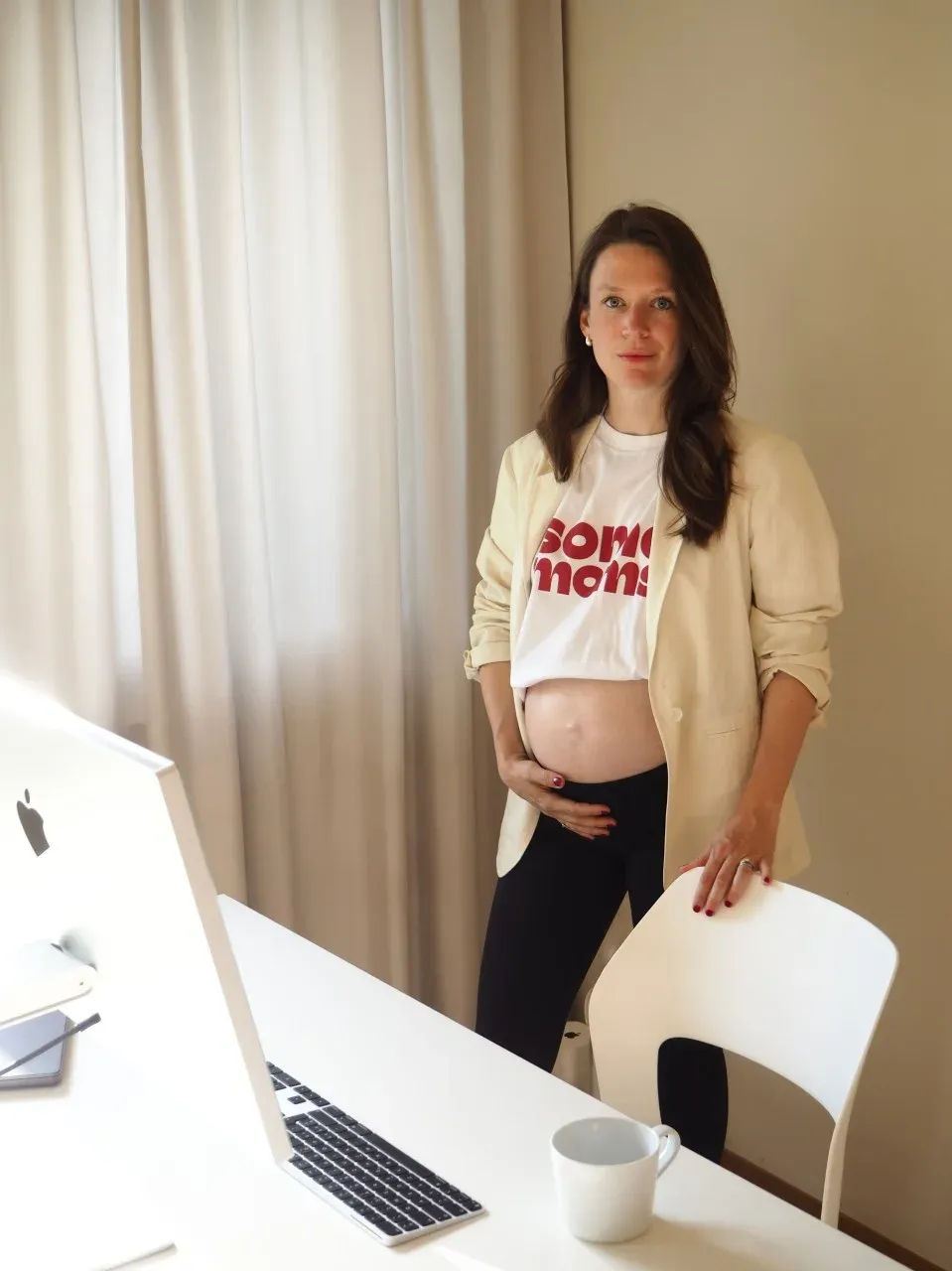 Natascha Müller-Kuhn steht schwanger im somemoms-Shirt an ihrem Schreibtisch